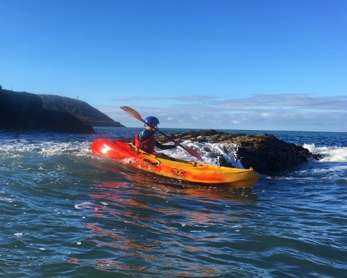 Playing with waves (rock hoping) whilst sea kayaking